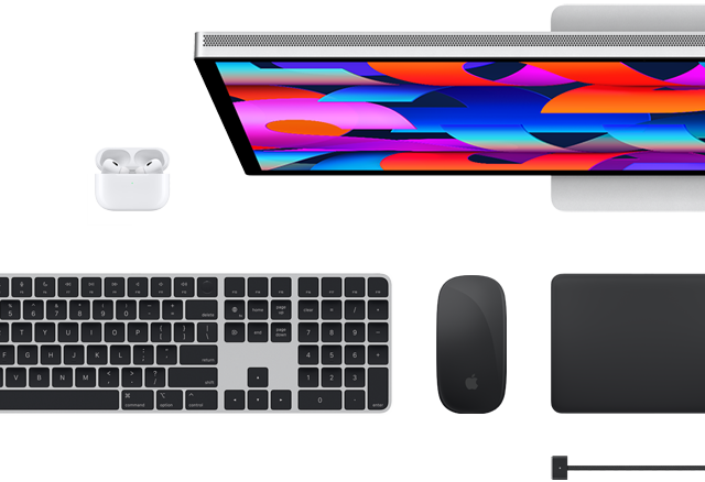 Udvalgt Mac-tilbehør set ovenfra: Studio Display, Magic Keyboard, Magic Mouse, Magic Trackpad, AirPods og MagSafe-opladerkabel