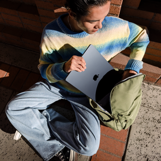 En person set forfra lægger en 15" MacBook Air ned i en taske