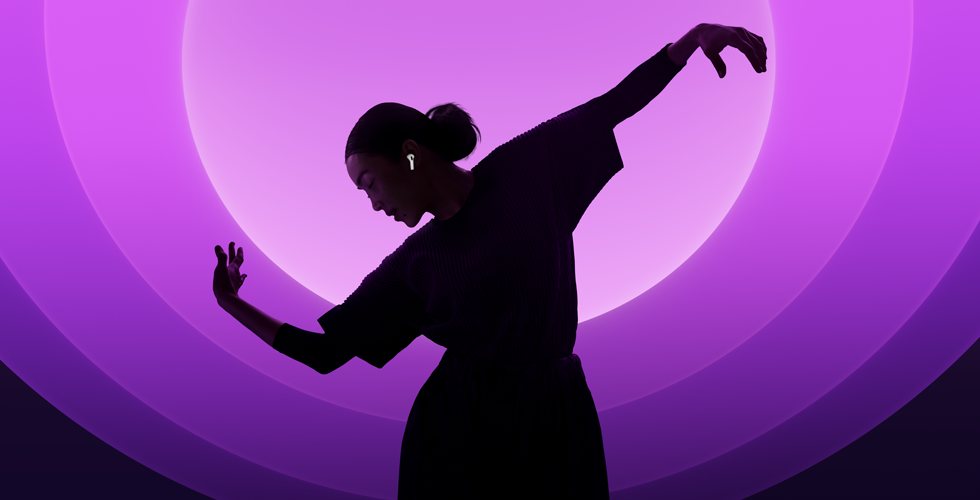 En person danser med AirPods 5 i ørerne mod en baggrund med flere farver