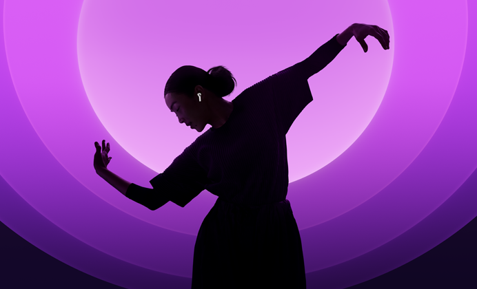 En person danser med AirPods 5 i ørerne mod en baggrund med flere farver